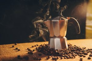 Italian coffee maker and coffee beans on canvas background