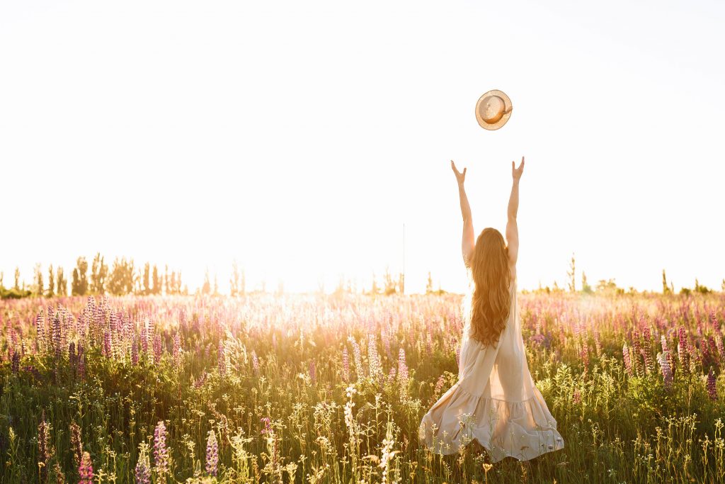 Imagen de una joven en un campo llenos de hierbas naturales y florecillas que nos despiertan todos los sentidos.