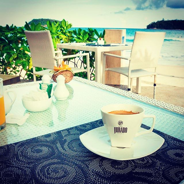 Una taza de nuestro mejor café caliente recién hecho, listo para tomar en una terraza junto al mar